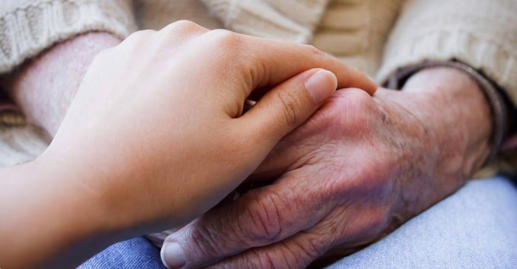 young hands tenderly holding elderly hands