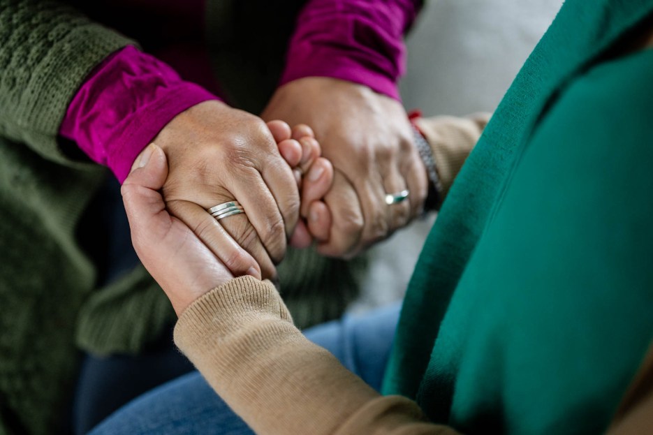 Close-up of a caregiver holding hands with a loved one, symbolizing caregiving support, comfort, and compassion.