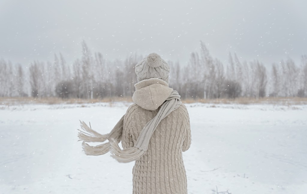 Caregiver standing in the snow, peacefully gazing at trees, embracing the serenity of nature