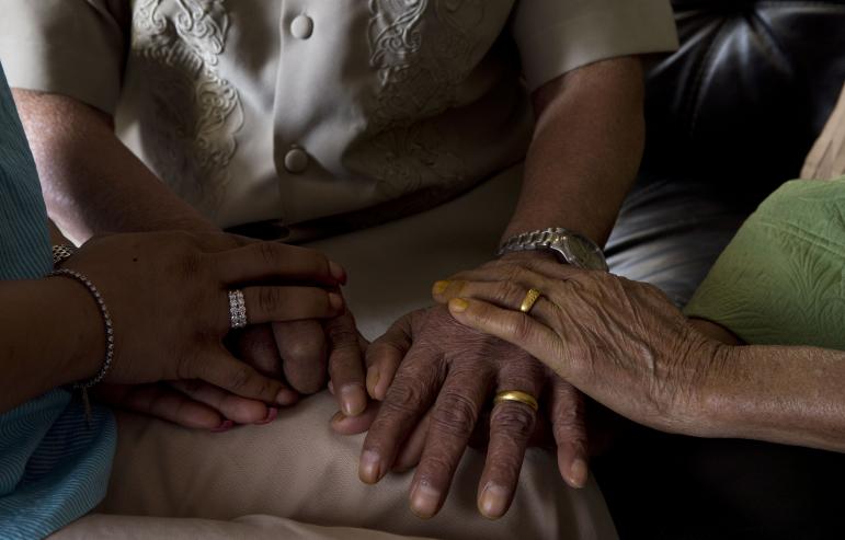 A caregiver daughter holding hands with her elderly parents