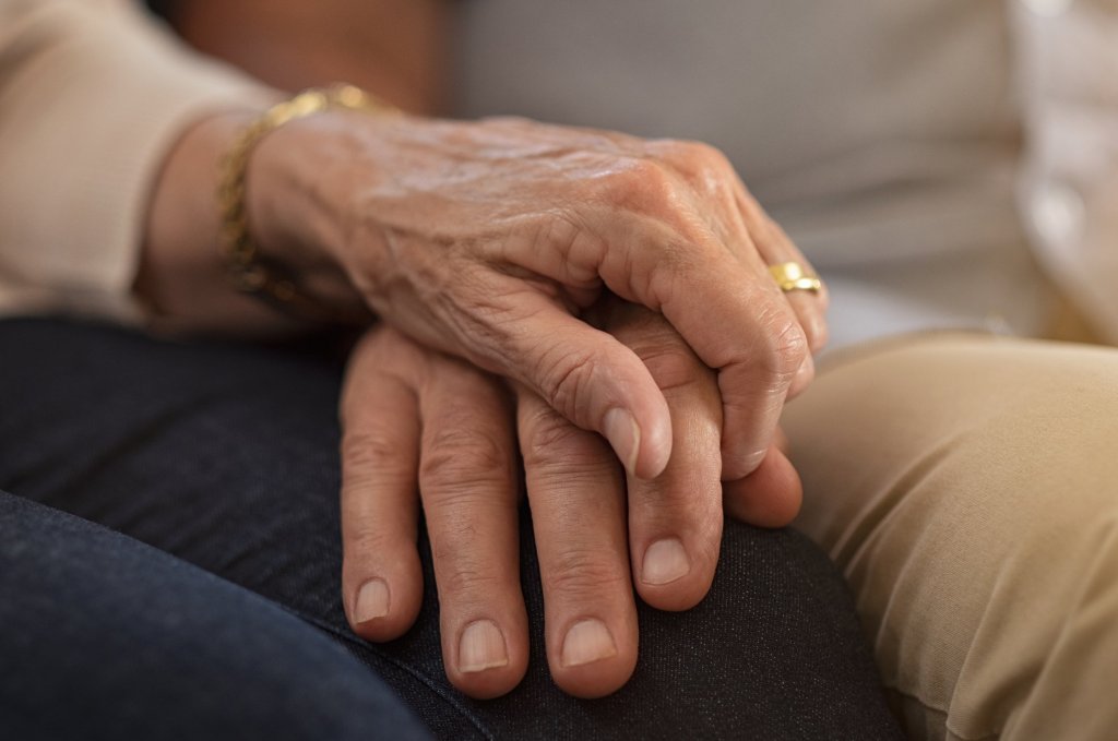 Elderly couple's hands clasped, conveying the strength and tenderness of caregiving