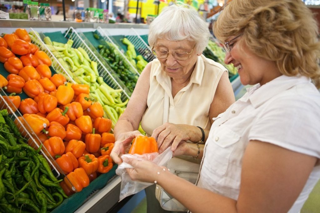 A caregiver helping her elderly mother pick out fresh produce