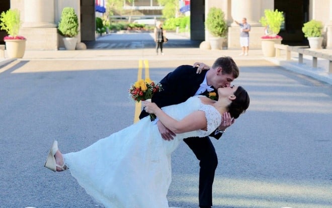 A bride with ALS kissing her now caregiver groom