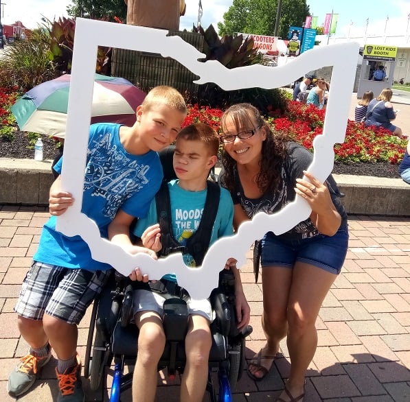 A caregiver mom posing with her sons with disabilities