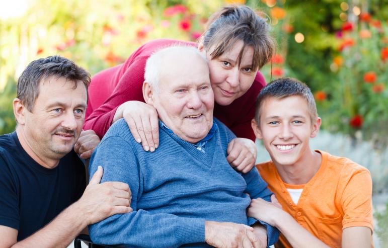 An elderly man posing for a picture with his caregiver children and their son