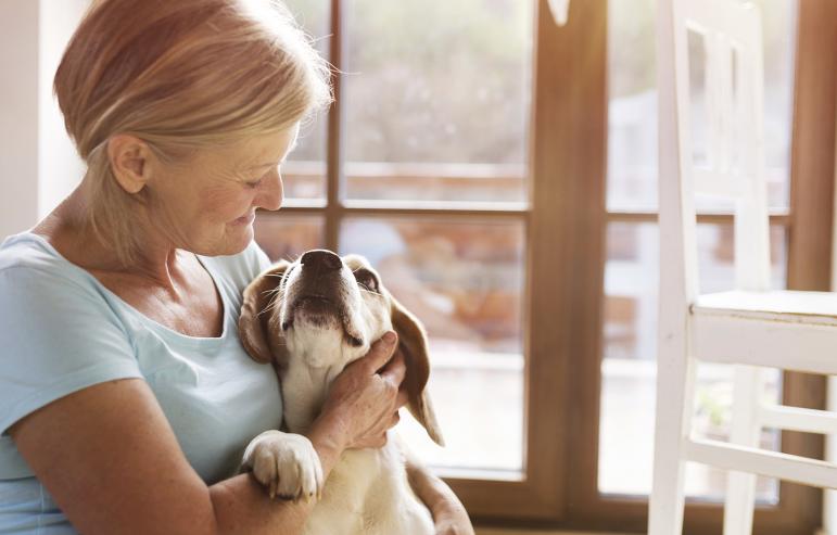 An elderly caregiver bonding with her dog, representing the importance of a companionship