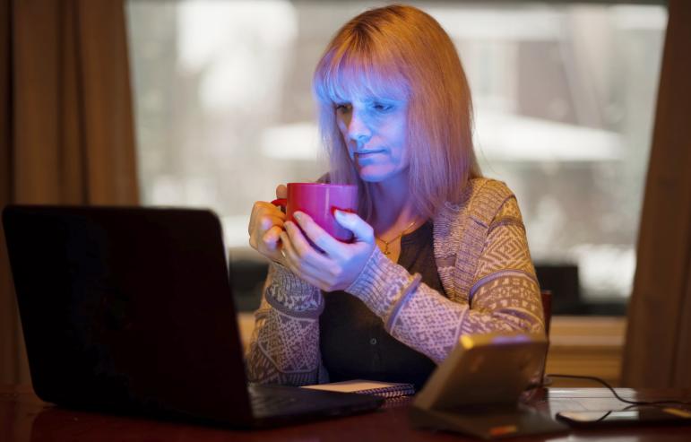 A caregiver holding a cup of tea while surfing the web