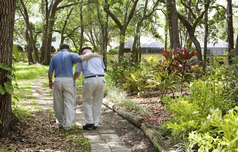 A caregiver enjoying a stroll at the park with his elderly father
