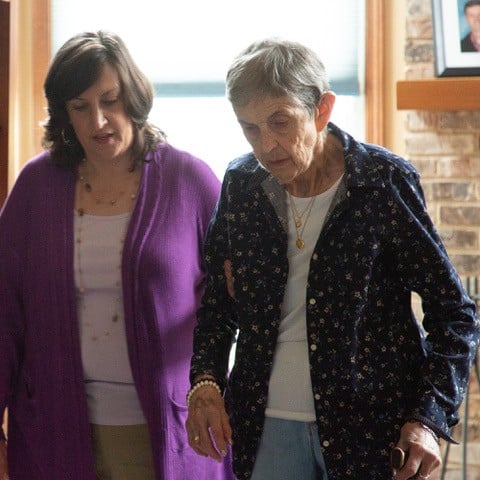 A caregiver helping her elderly mother walk
