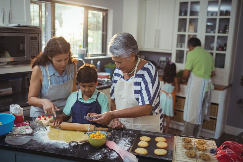 A caregiver with her children and her elderly parents baking cookies together