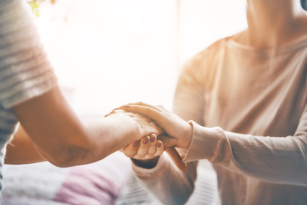 A caregiver holding hands with their loved one