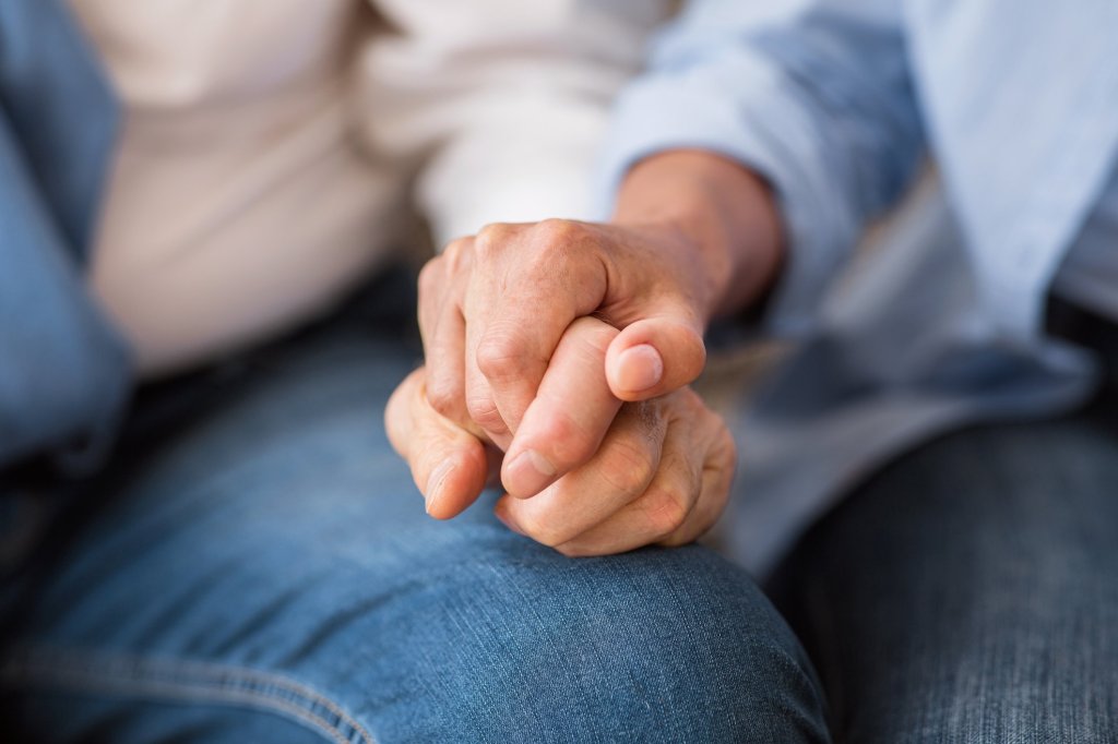 A caregiver holding hands with their elderly loved one