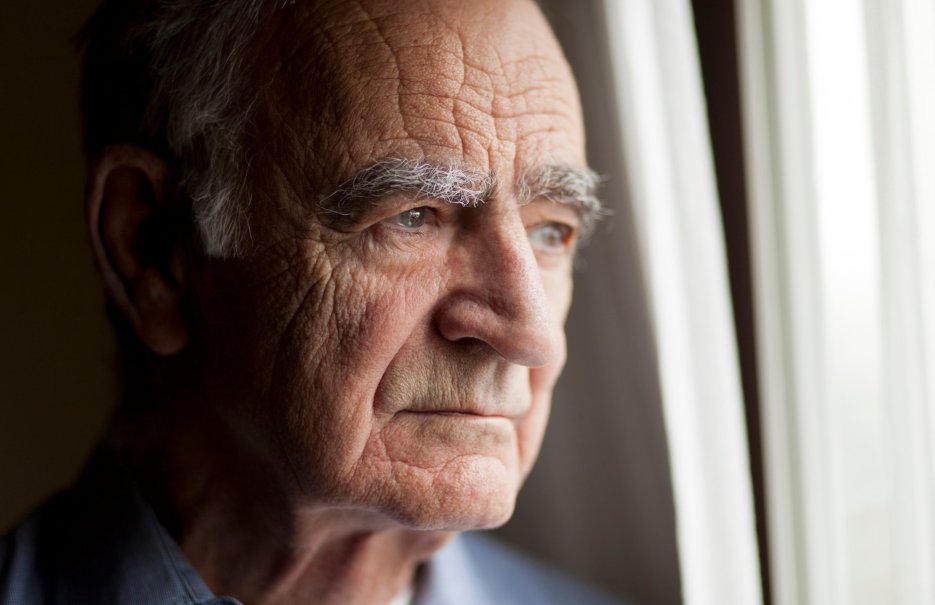 An elderly man gazing out the window