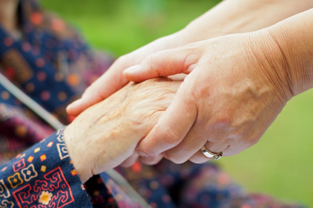 A caregiver holding hands with their elderly loved one