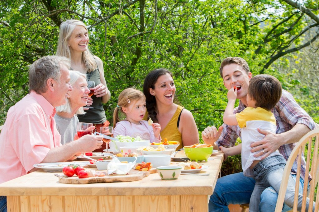 Joyful caregiver family enjoying a meal outdoors, sharing moments of happiness and togetherness