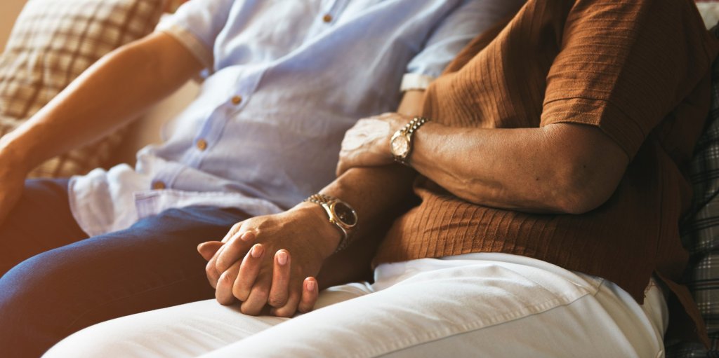 Loving caregiver couple embraces, holding hands and arms, symbolizing support and unity in caregiving