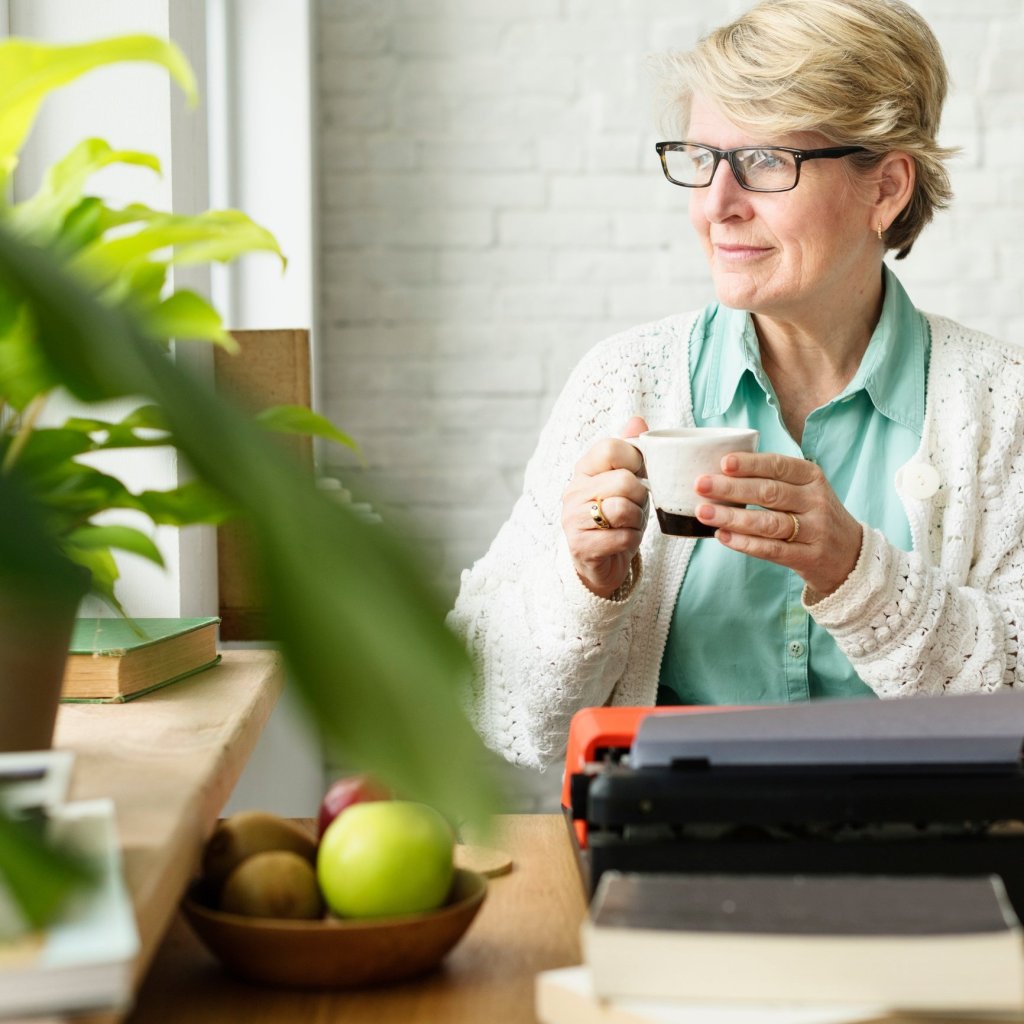 A caregiver holding her tea as she gazes out her window, taking a moment to reflect