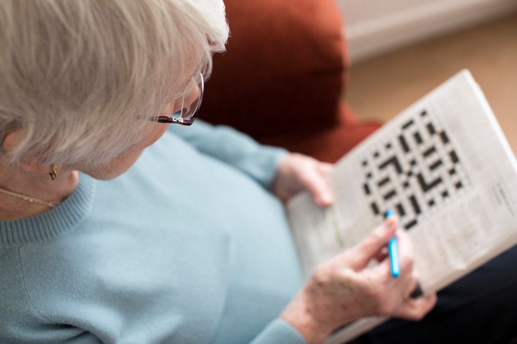 Elderly lady engaged in a crossword puzzle, enjoying one of the best brain games for older adults