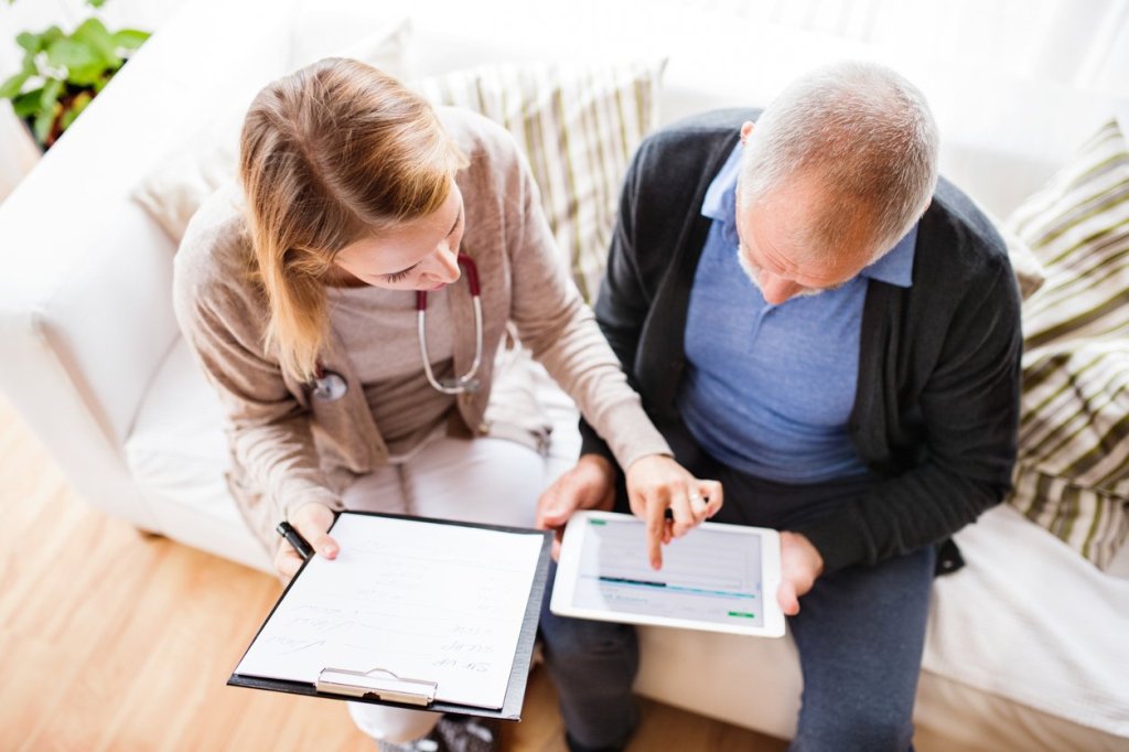 An older man and a doctor discussing medical records, exemplifying the vital role of caregiving in healthcare decisions