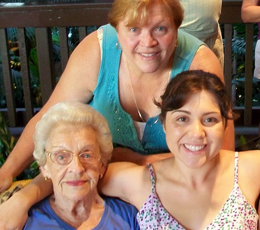 A caregiver posing for a picture with her elderly mother and another caregiver