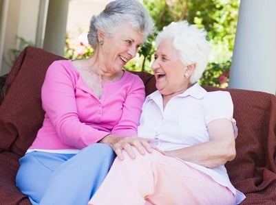 A caregiver and her elderly loved one happily chatting together