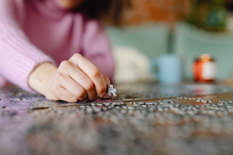 Person playing puzzles, concentrating on assembling the pieces