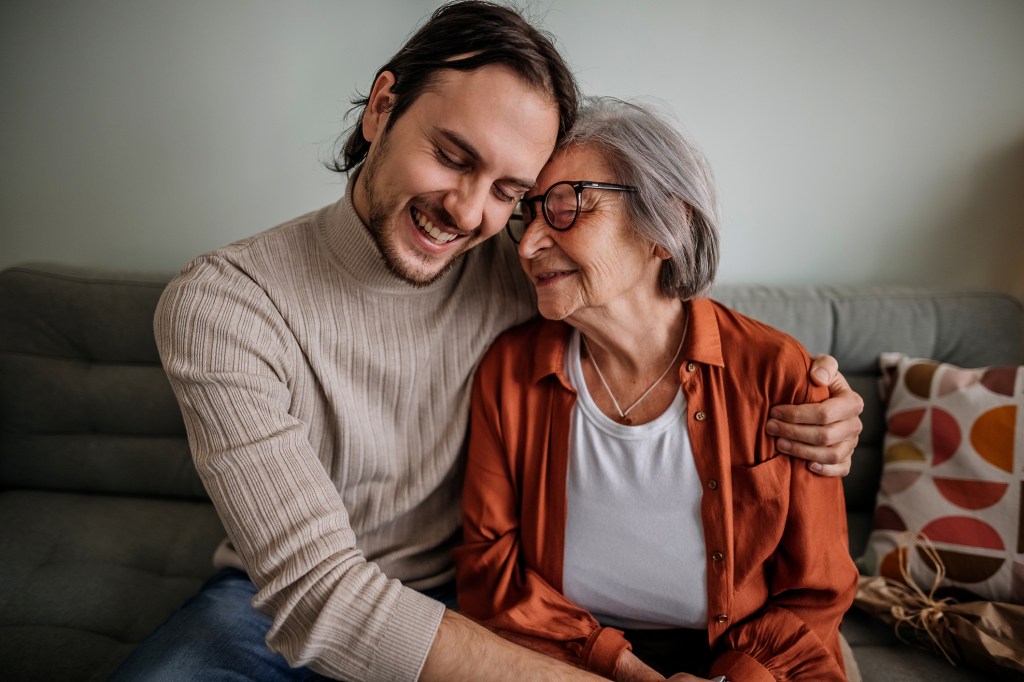 A caregiver son sitting next to his mother