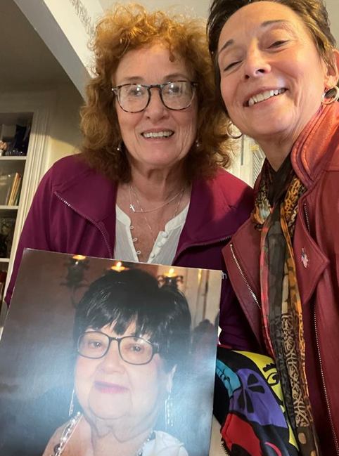 Two women holding a picture of a person

Description automatically generated