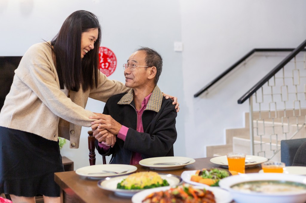 family bonding moment during chinese new year reunion dinner, mature daughter embracing with senior father