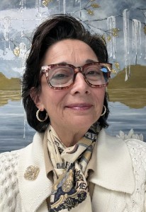 Linda Colangelo smiling warmly against an abstract background. Linda was the primary caregiver for her mother, Helene, and continues to dedicate her career to supporting others.